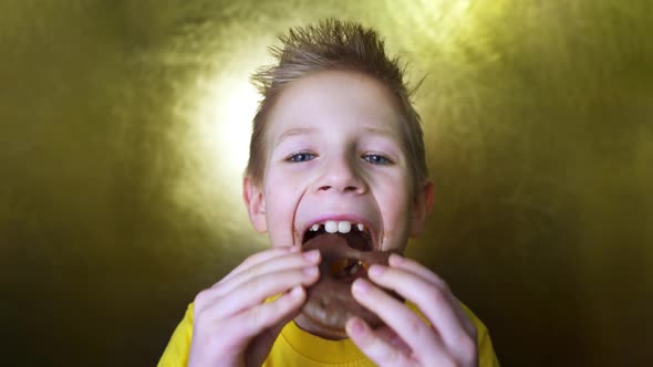 Happy kid eating a chocolate donut. Portrait of a boy with a face in chocolate