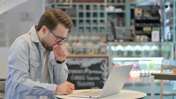 Man Coughing While Working on Laptop