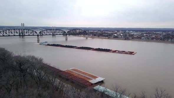 Aerial reveal view of a barge filled with coal being pushed by a tug boat on Louisville Kentucky Ohi