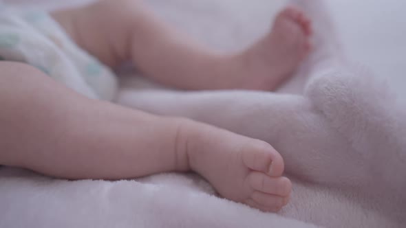 Closeup Little Caucasian Baby Legs Moving Lying on Soft Comfortable Bed Indoors