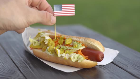 American patriotic hot dog on wooden board with USA flag.