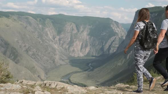 Male and Female Travelers Approach the Peak of the Mountain and Rejoice at Success Raising