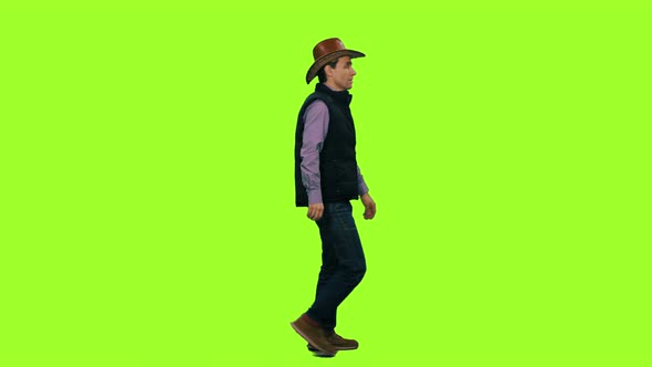 Side View of a Man in a Cowboy Hat Walks on Green Background