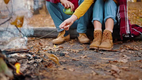 Unknown Couple Holding Cups of Tea Roasting Marshmallow on Burning Campfire