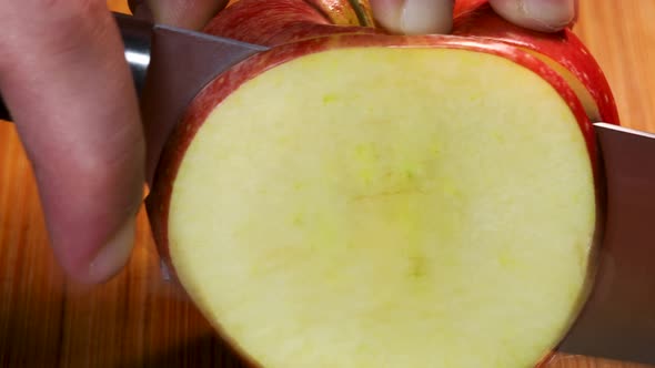 Sharp knife cuts a slice from a fresh red apple, macro shot detail close up in 4k.