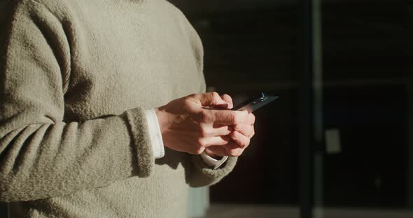 Closeup of Male Hands Typing a Message on Mobile Phone Outdoors