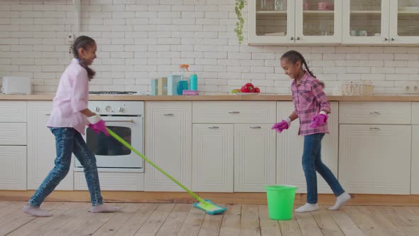 African American Sisters Mopping Kitchen Floor