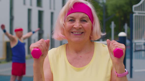 Senior Mature Woman Grandmother Doing Training Weightlifting Exercising with Dumbbells on Playground