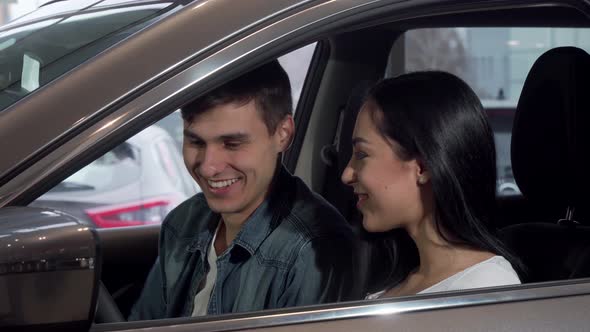 Young Happy Couple Choosing New Automobile at Dealership Salon