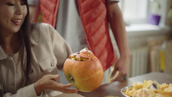 A Cute Young Lady Finishes Carving a Halloween Pumpkin