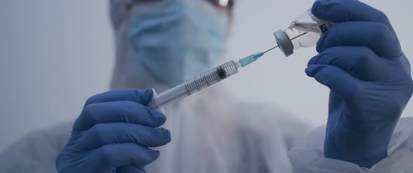 Person piercing a vaccine bottle and extracting fluid slow motion