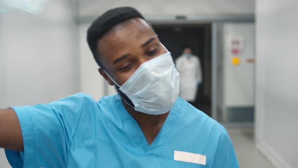 Portrait of Smiling African American Nurse at Work Walking in Corridor at Hospital