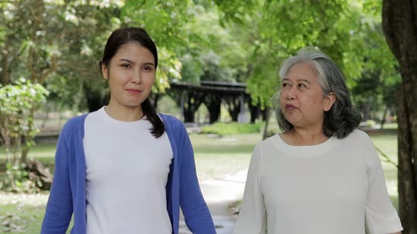 Elderly mother with happy Asian daughter smiling Take a walk and exercise in the park.