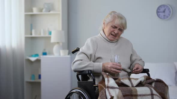 Elderly Lady in Wheelchair Suffering From Pain Taking Medications, Nursing Home