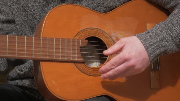 Man practicing acoustic guitar strumming cords Close-Up