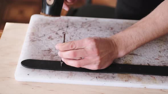 The Leather Craftsman Is Making Holes in a Hand-made Belt