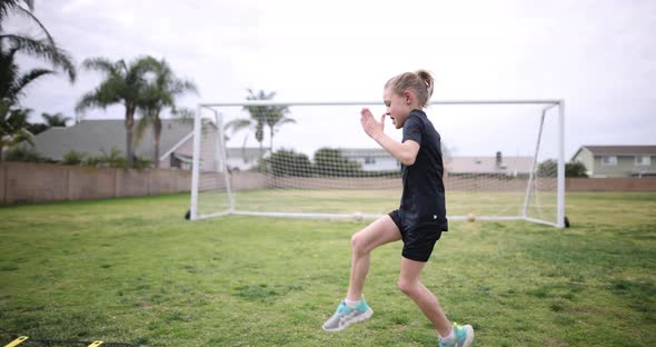 A young athlete does high knees as part of her warm up before soccer practice.