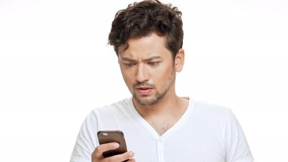 Displeased Young Handsome Man Looking at Phone Sighing Over White Background