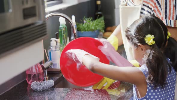 Grandmother and granddaughter washing dishes in the sink