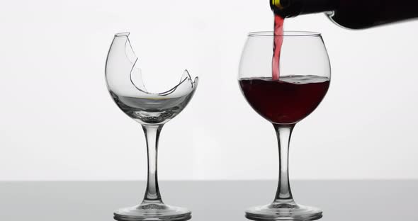 Wine. Red Wine Pouring Into Normal and Broken Wine Glasses on the Wet Surface