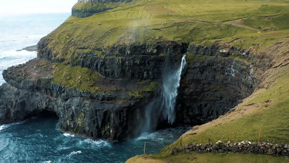 Flying Around a Hiker at the Gasadalur Waterfall on Faroe Islands, Denmark