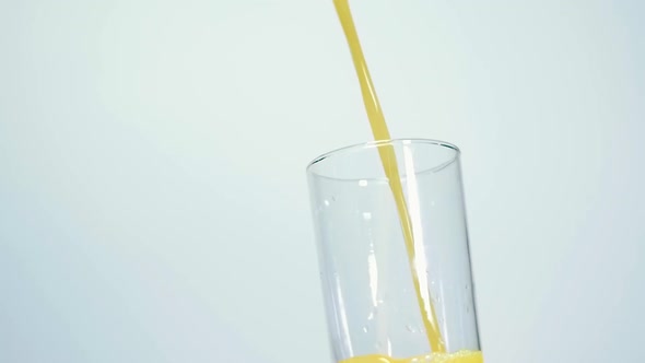 Slow Motion Shot of Fresh Orange Juice Being Poured in a Glass on white background Close up Shallow