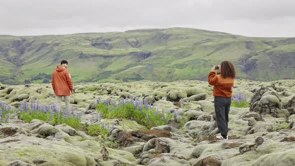 Woman Photographing Man In Mossy Landscape