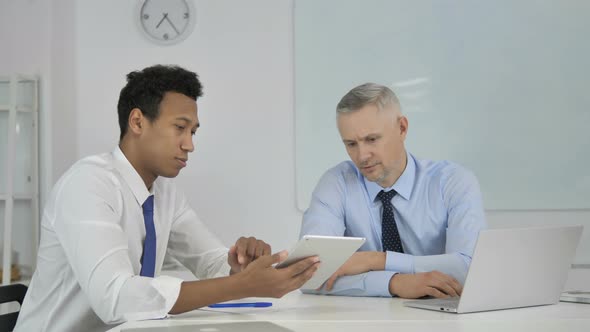 African Businessman Discussing New Plan on Tablet with Senior Businessman