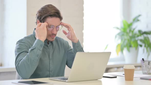 Middle Aged Man with Laptop Having Headache