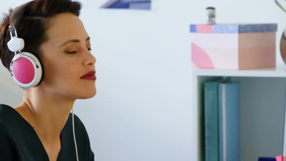 Side view of Caucasian Businesswoman in headphones working on computer at desk in office 4k