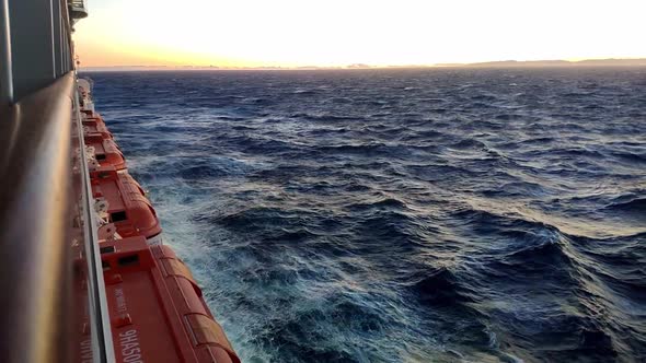 Beautiful horizon view at open sea from a cruiser navigating on sunset hour. Sea is agitated. Waves