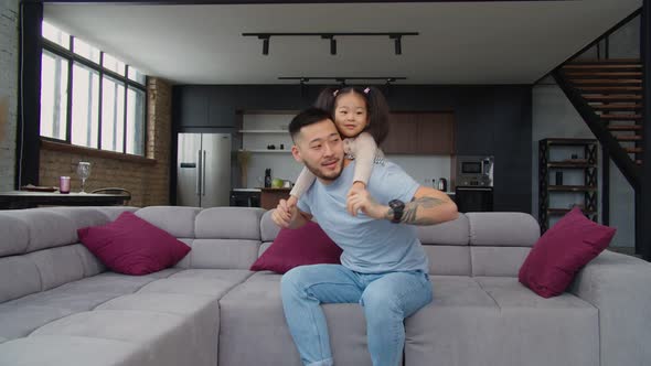 Happy Asian Dad and Toddler Daughter Having Fun on Sofa