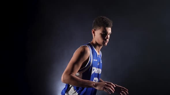 Young Guy in the Uniform of a Basketball Player Posing in the Studio on a Black Background in the