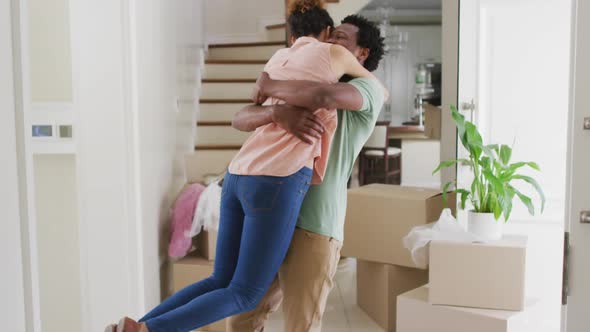 Happy biracial couple hugging with joy in new house