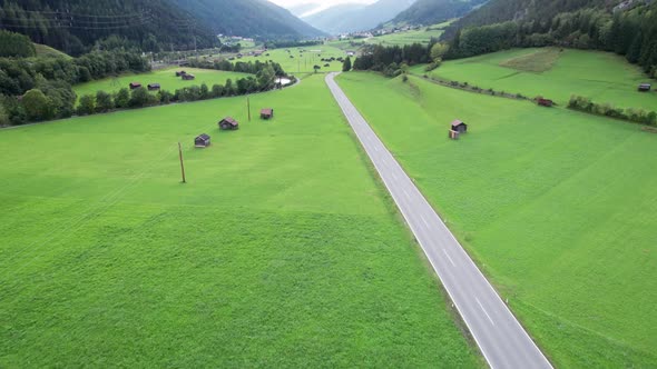 Empty Road in Austrian Valley Between Green Fields in the Alps Aerial View