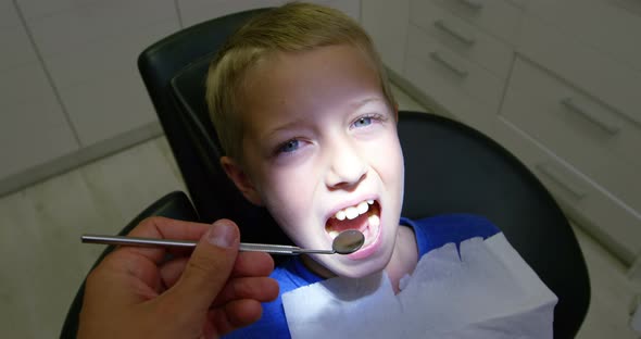 Dentist examining a young patient with tools