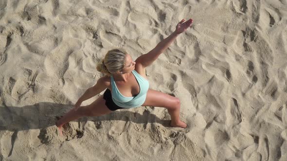 Overhead shot of a young attractive woman doing yoga on the beach