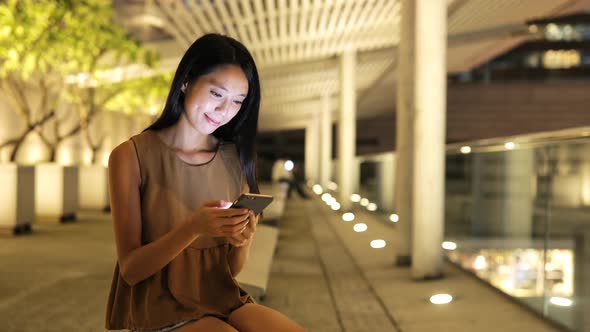 Woman looking at mobile phone in city at night 