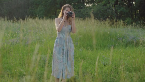 Confident Young Female Photographer Raising Up Camera and Taking Photo of Nature Outdoors. Wide Shot