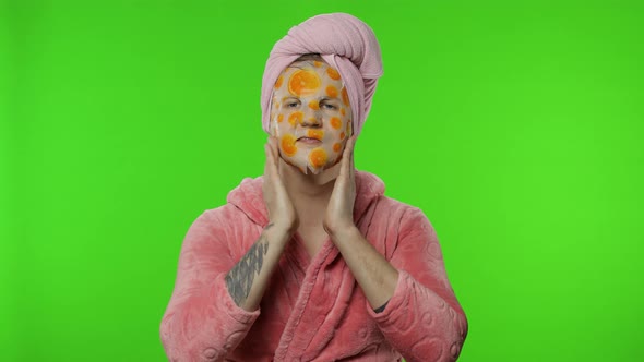 Young Man in Bathrobe with Face Mask Looking at Camera, Smiling