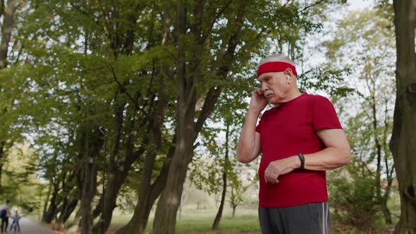 Senior Runner Man in Park Using Smart Watch, Tracking Distance, Checking Pulse After Fitness Workout
