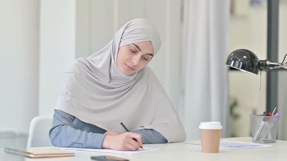 Pensive Young Arab Woman Writing on Paper