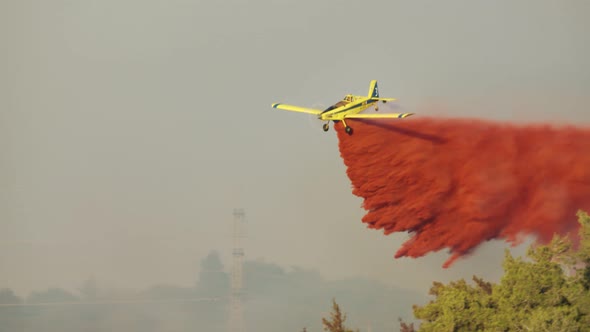 Fire fighter plane drops fire retardant on a forest fire in the hills