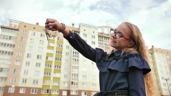 A Young Schoolgirl Holds the Keys to a New Apartment