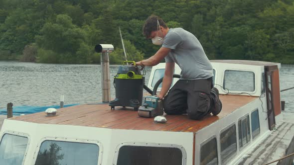 Young man begins taslk of ring varnish from wood boat forecabin