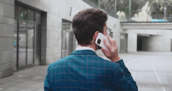 Rear Back View on the Caucasian Businessman in Glasses Walking the Street at the Office Center and