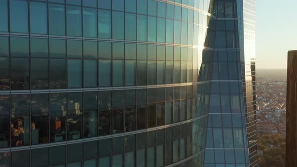 Ascending Footage Along Windows and Glass Wall of Office Skyscraper Reflecting Buildings in Town and