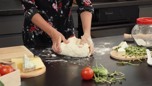 Hands knead scone dough on kitchen table.