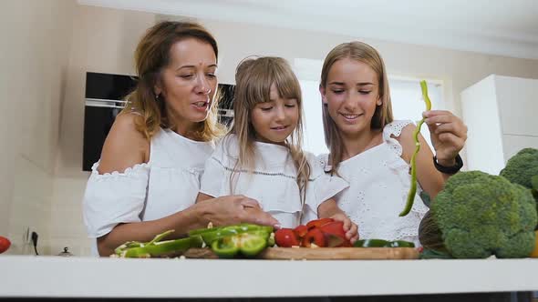 Beautiful Mother Teaches Her Younger Daughter to Cut a Pepper 