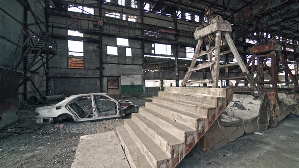 Old construction with stairs and antique car frame on the background of broken plant.